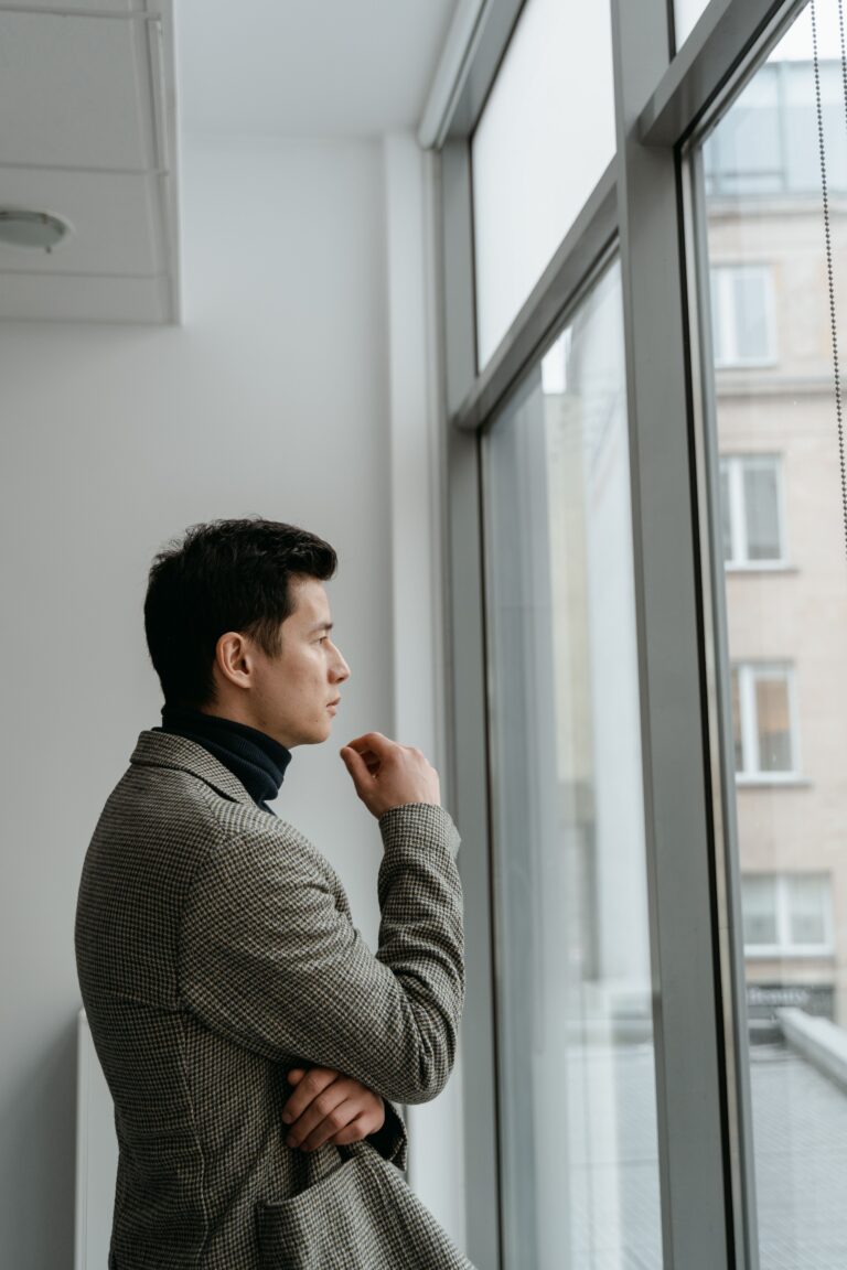 Jonge man bij een raam, peinzend over erectieproblemen