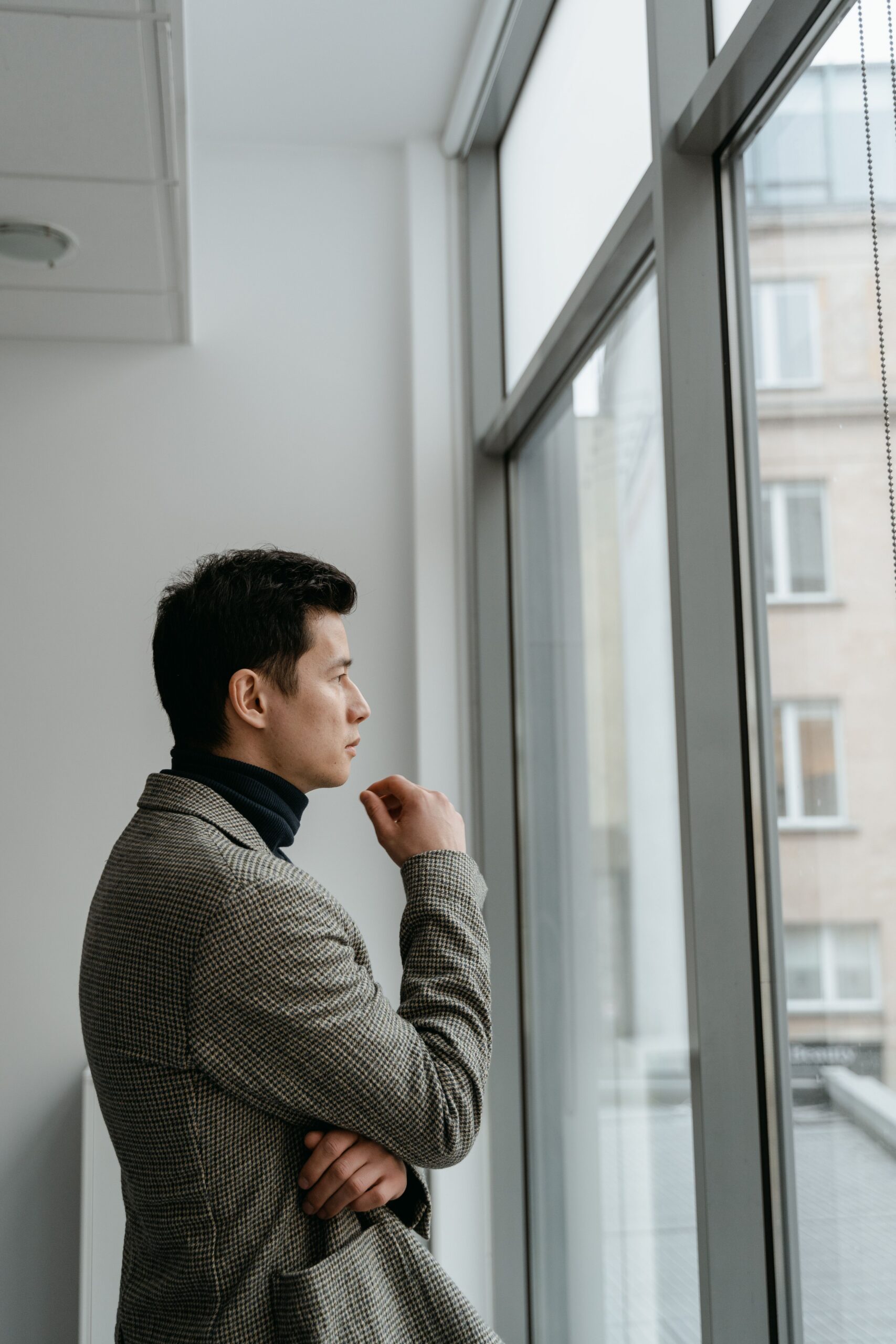 Jonge man bij een raam, peinzend over erectieproblemen